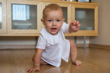 Evin içinde sürünen sevimli küçük bir çocuk. Mutlu bebek yerde kameraya doğru sürünüyor.