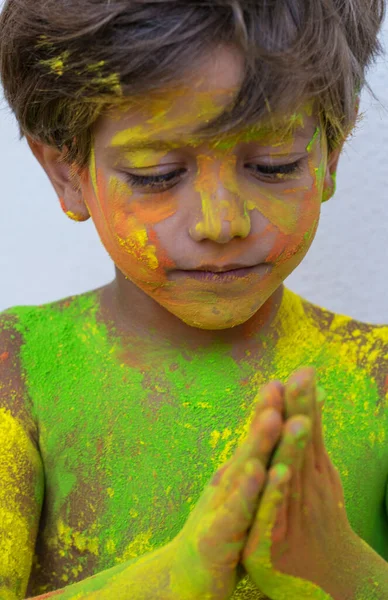 Portrait of child with colors in the face. Portrait of cute child drenched in colored powders during Holi