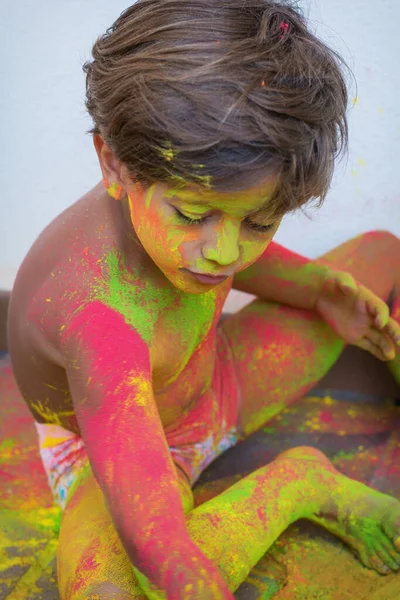 Portrait of child with colors in the face. Portrait of cute child drenched in colored powders during Holi