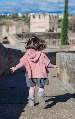 Ortaçağ şatosunda oynayan ve koşan bir kızın arka görünüşü