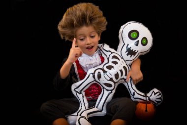 Cadılar Bayramı partisi için vampir kostümü giymiş güzel ve komik bir çocuk ve iskelet bir bebek. Şaka mı Tedavi mi?