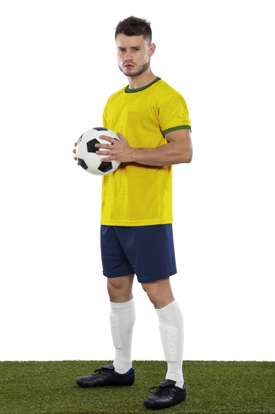 黄色と緑のシャツと白い背景の上の手にボールを持つ草の若いサッカー選手 — ストック写真