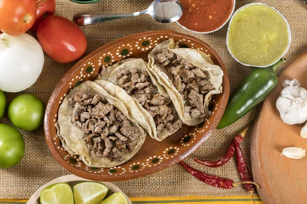 Typical Mexican food dishes with sauces on colorful table. Roast beef tacos.