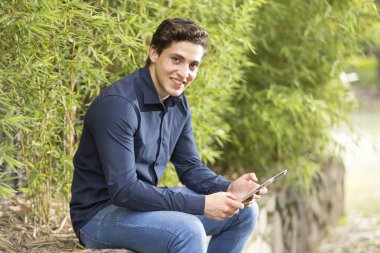 Önden görünüş portresi oturmuş gülümseyen genç bir işadamı ve manifatura telefon