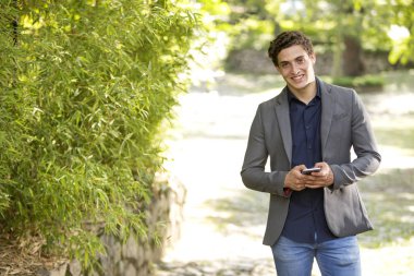 Kamera ve manifatura doğru telefon üzerinde yürüme gülümseyen genç bir işadamı portresi önden görünüm