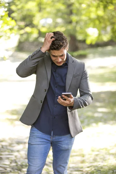 Elinde Cep Telefonu Ile Bahçede Oturan Genç Sorunlu Adamı — Stok fotoğraf