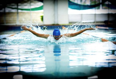Kelebek yüzme tekniği olan genç bir atletik.