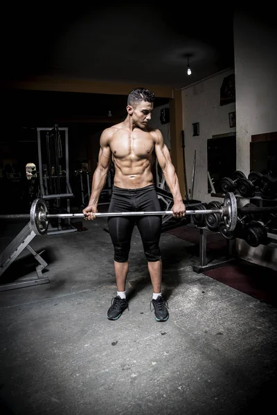 Young man exercising in dark and old gym