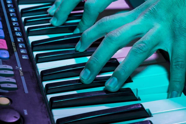 Musician\'s hand is playing a keyboard in low light background