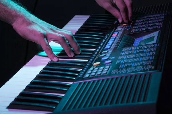 Musician's hand is playing a keyboard in low light background