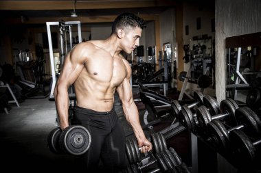 Genç adam karanlık ve yaşlı spor salonunda egzersiz yapıyor.