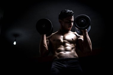 Genç adam karanlık ve yaşlı spor salonunda egzersiz yapıyor.