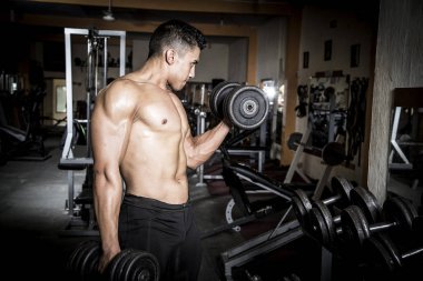 Genç adam karanlık ve yaşlı spor salonunda egzersiz yapıyor.