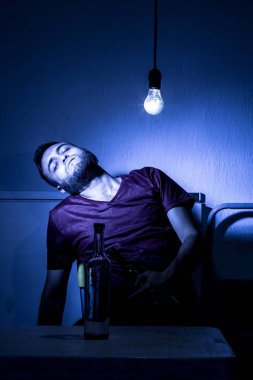 Sakallı genç adam, alkolizm, sigara ve uyuşturucu bağımlılığında kaybolmuş.