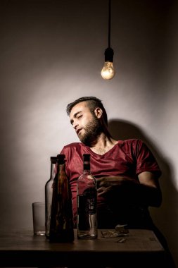 Sakallı genç adam, alkolizm, sigara ve uyuşturucu bağımlılığında kaybolmuş.