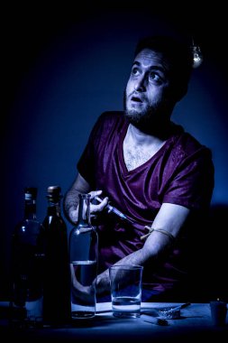 Sakallı genç adam, alkolizm, sigara ve uyuşturucu bağımlılığında kaybolmuş.