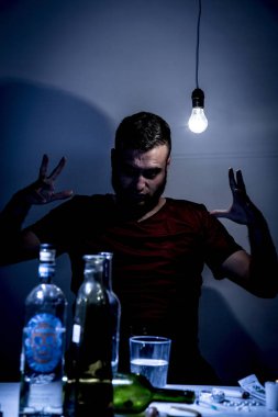 Sakallı genç adam, alkolizm, sigara ve uyuşturucu bağımlılığında kaybolmuş.