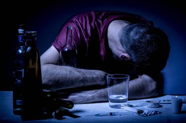 Sakallı genç adam, alkolizm, sigara ve uyuşturucu bağımlılığında kaybolmuş.