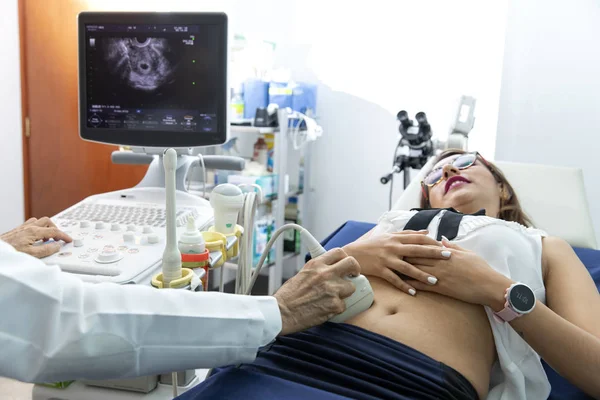 Doctor performing health exams on a woman. Technician in ecosonography.