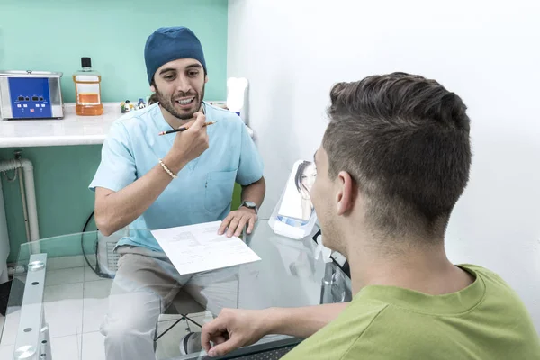 A young male dentist and a patient. Dentist office lifestyle scene. Doctor practice. Patient health care