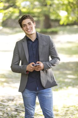 Kamera ve manifatura doğru telefon üzerinde yürüme gülümseyen genç bir işadamı portresi önden görünüm