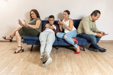 Gerçek Latin ailesi, baba, anne, oğul ve kız mavi koltukta oturuyor ve her biri kendi cep telefonuyla iletişim kuruyor..