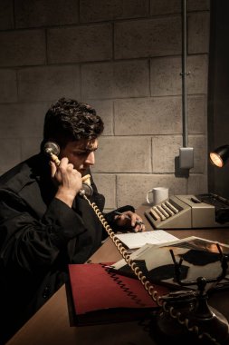 Bir dedektifin ofisinde karanlık ve dramatik bir sahne. Ağır duman. Masada çalışan bir dedektif.