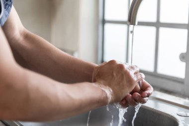 COVID-19 hastalıklı genç adam karantinada. Ellerini yıkayan adam. 