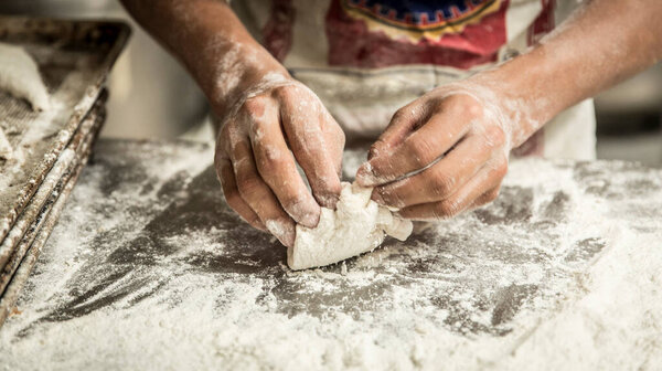 hands of the teacher baker in the bread production on the table