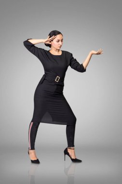 Stüdyoda siyah giysiler içinde poz veren güzel esmer manken..
