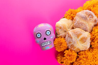 Parlak pembe arka planda tipik Meksika kafatası ve cempazuchitl çiçekleri kompozisyonu.