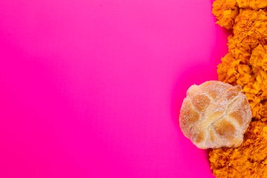 Parlak pembe arka planda tipik Meksika kafatası ve cempazuchitl çiçekleri kompozisyonu.