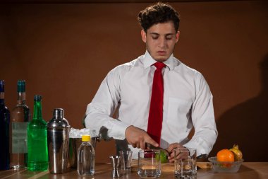 Barmen barda alkollü bir içecek hazırlıyor. Yanında da bir bardak likör.. 