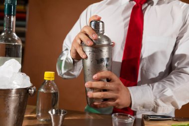 Barmen barda alkollü bir içecek hazırlıyor. Yanında da bir bardak likör.. 