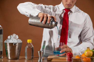 Barmen barda alkollü bir içecek hazırlıyor. Yanında da bir bardak likör.. 