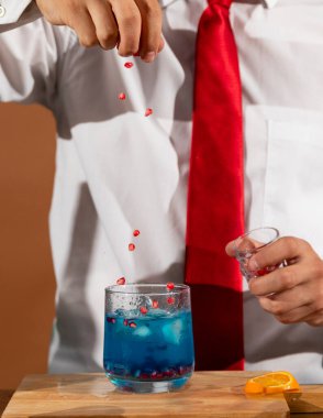 Barmen barda alkollü bir içecek hazırlıyor. Yanında da bir bardak likör.. 