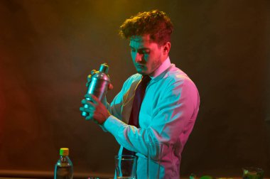 Barmen barda alkollü bir içecek hazırlıyor. Yanında da bir bardak likör.. 