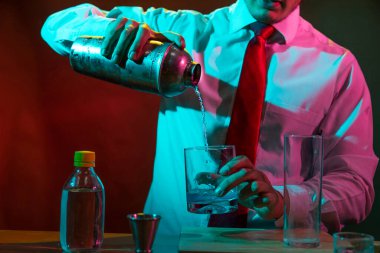 Barmen barda alkollü bir içecek hazırlıyor. Yanında da bir bardak likör.. 