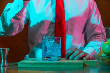 Barmen barda alkollü bir içecek hazırlıyor. Yanında da bir bardak likör.. 