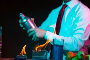 Barmen barda alkollü bir içecek hazırlıyor. Yanında da bir bardak tekila. Dramatik ışıklar