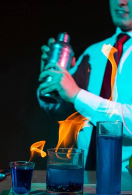 Barmen barda alkollü bir içecek hazırlıyor. Yanında da bir bardak tekila. Dramatik ışıklar