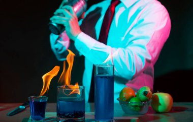 Barmen barda alkollü bir içecek hazırlıyor. Yanında da bir bardak tekila. Dramatik ışıklar