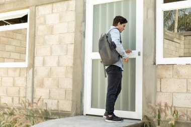 Yakışıklı ve zarif bir adam okula gidiyor. Elinde kahveyle kameraya bakıyor.