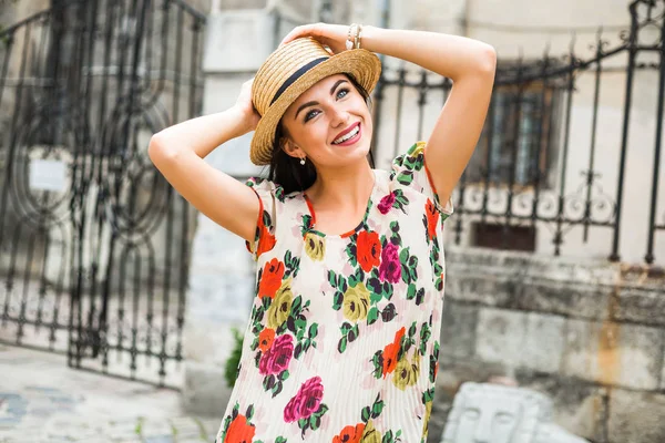 young beautiful girl in summer dress, straw hat. Travels around the European city in the summer. Cheerful, smiling lady. old houses, paving stones, vintage style, old Europe
