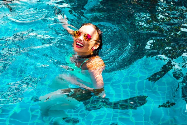 the girl is swimming in the pool at the hotel smiling and having fun. The concept of summer holidays in the hotel
