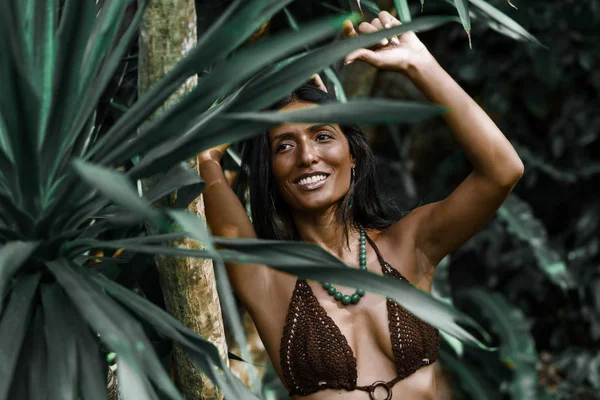 Bright tanned Turkish woman on a tropical island, dressed in a handmade swimsuit, summer vacation, travel, freedom, happiness