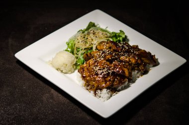 Teriyaki tavuk beyaz plaka ve koyu arka plan.