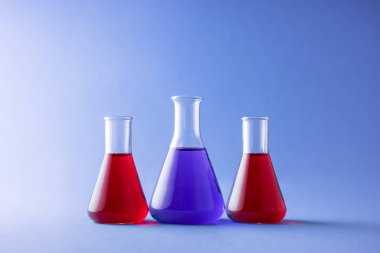 Renkli arka plan üzerinde üç erlenmeyer şişeler