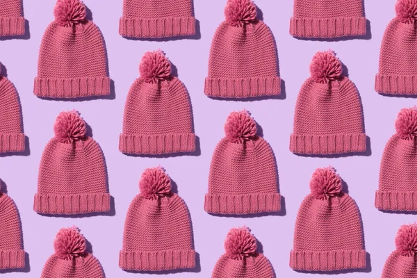 Knit winter hats organized in a row over purple background