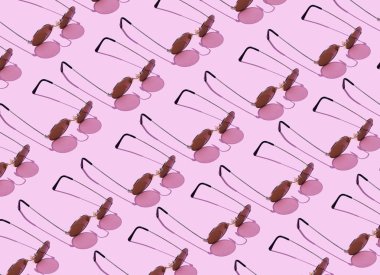 Pembe arka plan üzerinde düzenlenen yuvarlak güneş gözlüğü